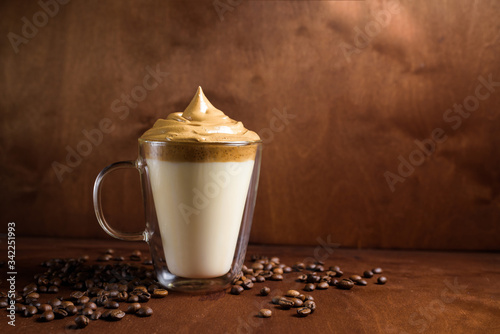 cold dalgon coffee in clear glasses on a dark wooden background. foam from sugar and instant coffee is whipped with a mixer over cold milk. Korean and Indian whipped coffee.