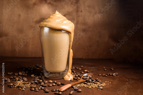 cold dalgon coffee in clear glasses on a dark wooden background. foam from sugar and instant coffee is whipped with a mixer over cold milk. Korean and Indian whipped coffee. photo