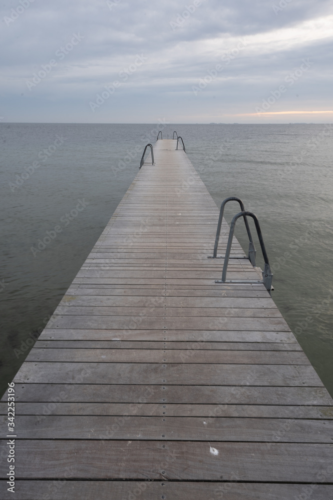 Obraz premium jetty in the ocean, no people. there is a ladder on the jetty. cloudy day