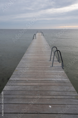 jetty in the ocean, no people. there is a ladder on the jetty. cloudy day