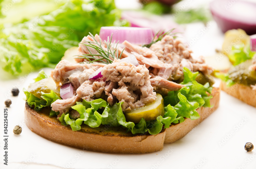 Tuna sandwiches with pickled cucumbers and onions on parchment paper