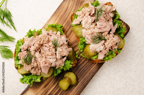 Obraz na płótnie Flat lay view at homemade tuna salad sandwiches on cutting board with pickles as