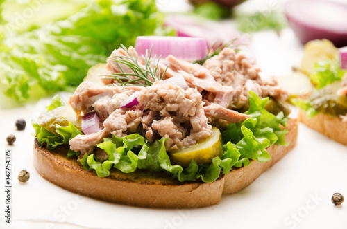 Obraz na płótnie Tuna sandwiches with pickled cucumbers and onions on parchment paper w salonie