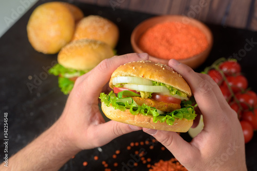 vegan Burger with lentil cutlets . vegan food with vegetable protein, herbs, tomatoes, onions on a dark wooden background. the view from the top.