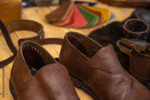 Workplace artisan. Tools for working with leather. Leather products. Boots. The workshop of the shoemaker. Wooden table.