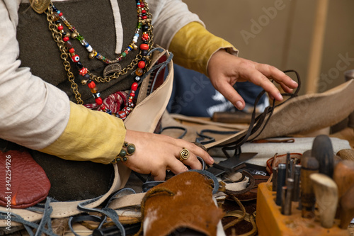 A merchant in his workshop.  Dressed in a traditional costume. On hands in a neck jewelry from copper.