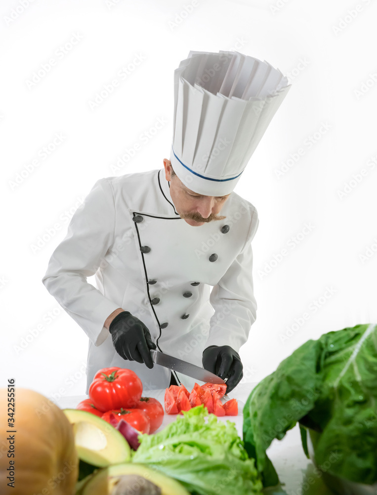 Chef cook cut tomatoes with a knife at the white table with a vegetables Chef cook cut tomatoes with a knife at the white table with a vegetables