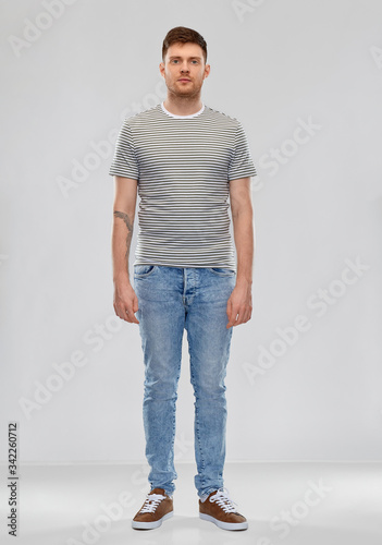 people concept - young man in striped t-shirt and jeans over grey background