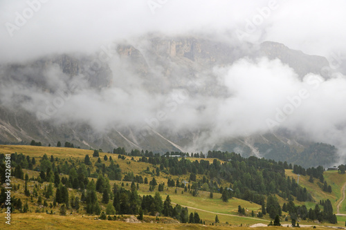 The peaks of the Dolomites in Italy are covered in fog. Early wet foggy morning. Beginning of autumn. Clean fresh air, lack of people. Selective focus.