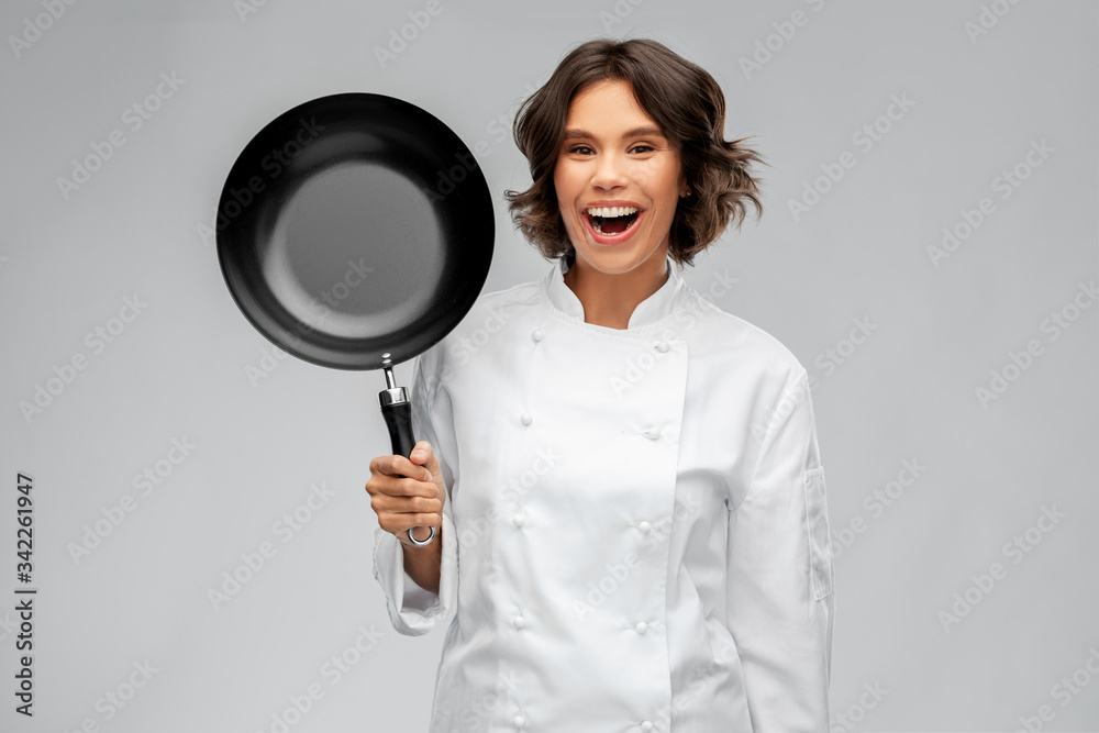 cooking, culinary and people concept - happy smiling female chef in toque with frying pan over grey background cooking, culinary and people concept - happy smiling female chef in toque with frying pan over grey background