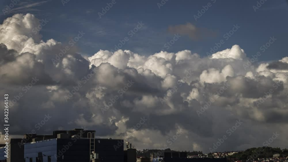 Timelapse of white clouds dancing in a dark sky of Santiago de Compostela in Spain with some buildings in the background. Timelapse of white clouds dancing in a dark sky of Santiago de Compostela in Spain with some buildings in the background.