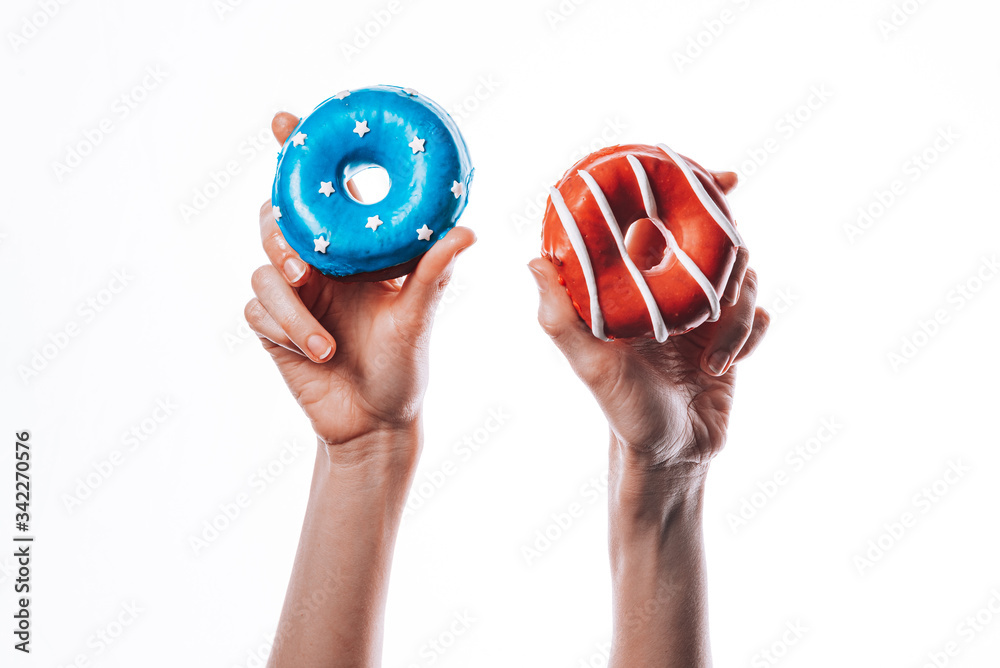 donuts with red icing and white lines and with blue icing and white stars in their hands on a white background donuts with red icing and white lines and with blue icing and white stars in their hands on a white background
