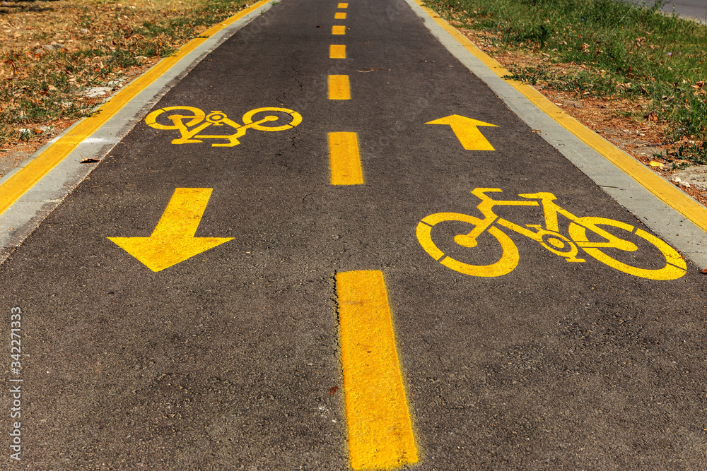 Bicycle sign on bicycle lane sdvustoronnim cyclists in urban parkland. Healthy lifestyle. Equipped track loves biking nature walks Bicycle sign on bicycle lane sdvustoronnim cyclists in urban parkland. Healthy lifestyle. Equipped track loves biking nature walks