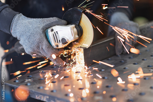 Photography A metal worker cuts a rectangular metal pipe with an angle grinder