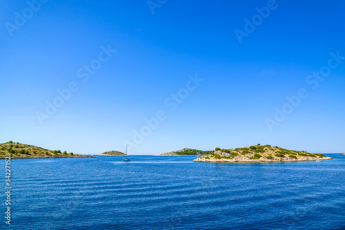 Adriatic coast with rocky beach, small islands, boats and sailing yachts in the blue sea, Croatia, Dalmatia