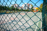 Basketball court behind green mesh wire fence in public park. Basketball sport concept.