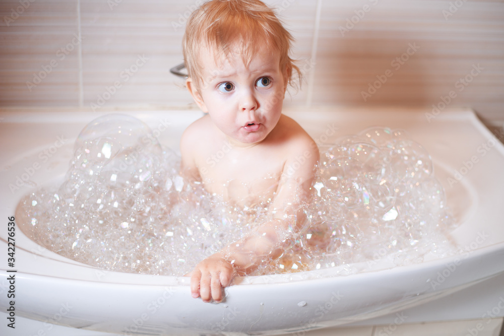 Funny child playing with water and foam in a bathroom. Funny child playing with water and foam in a bathroom.