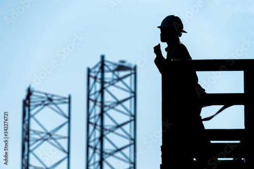Silhouette of a Barge Foreman giving instruction on a walkie-talkie to team of roughneck at an oil rig photo