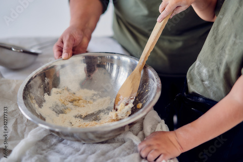 boy with his grandmother knead the dough on a light background