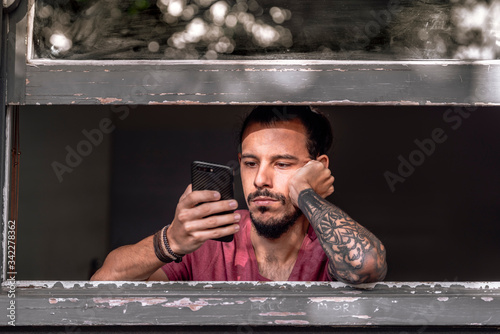 A young man bored during his lockdown due to a smartphone overdose. In order to prevent coronavirus spread, he stays at home to stay safe. He has smartphone addiction . Concept: Coronavirus Covid 19