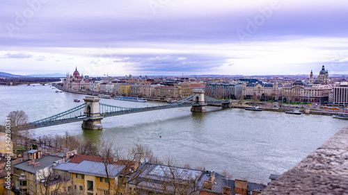 View of Chain Bridge, Hungarian Parliament and River Danube form Castle Garden Bazaar, Budapest Hungary. Image in shades of purple.