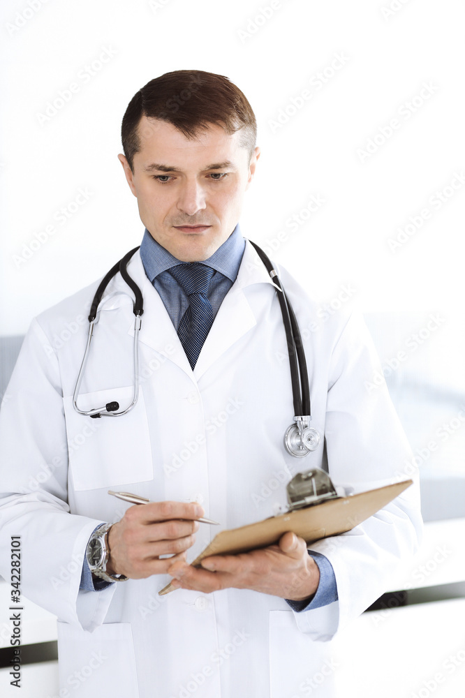 Doctor man using clipboard for filling up medication history records. Perfect medical service in clinic. Physician at work in hospital. Medicine and healthcare concepts Doctor man using clipboard for filling up medication history records. Perfect medical service in clinic. Physician at work in hospital. Medicine and healthcare concepts