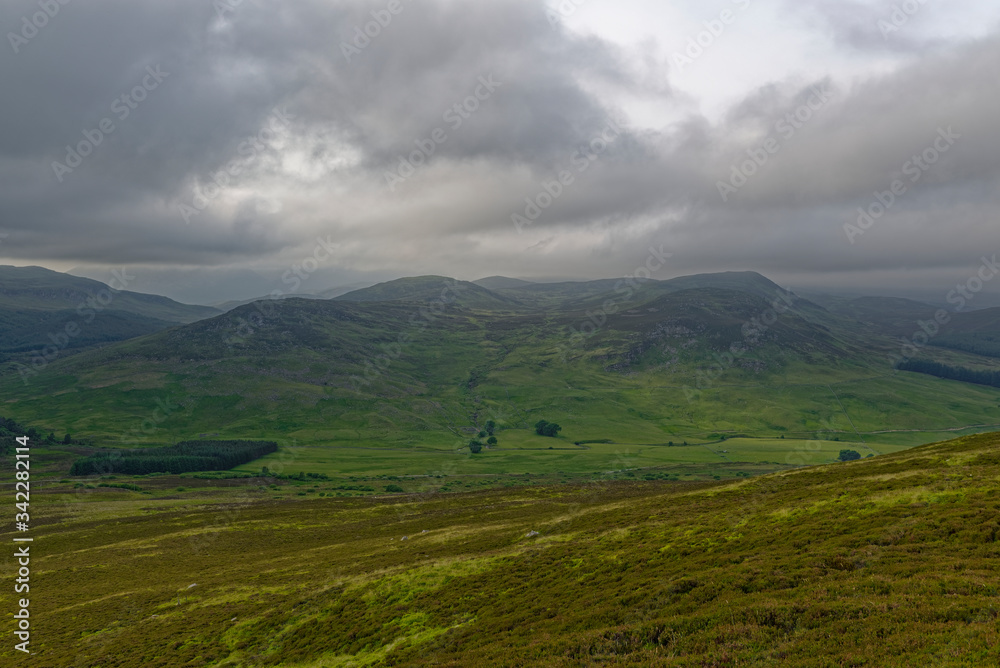 Glen Brerachan near to Pitlochry with the A924 road and River Brerachan running through it on the Valley Floor under dark storm clouds.