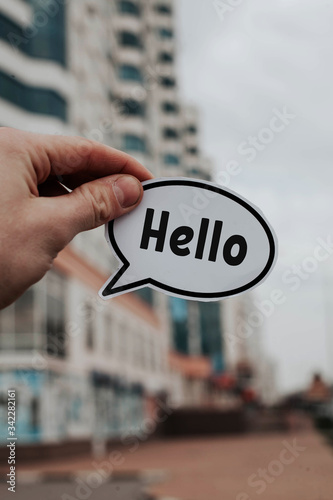 a man's hand holds a piece of paper with the inscription Hello photo