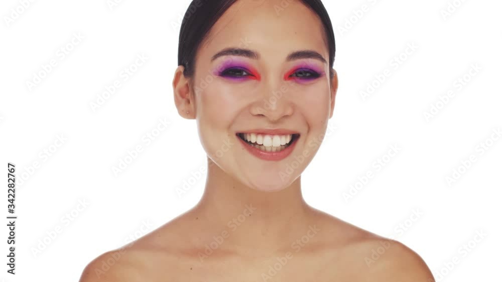 A surprised smiling half-naked asian woman with bright fashion eye makeup is shaking her head positively isolated over white background in studio A surprised smiling half-naked asian woman with bright fashion eye makeup is shaking her head positively isolated over white background in studio