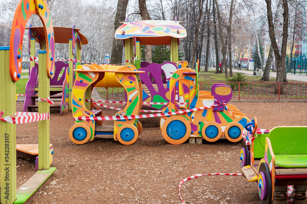 Obraz premium Children's playground shrouded in a prohibitory signal tape. Children cannot walk and play outside during the coronavirus epidemic. COVID-19.