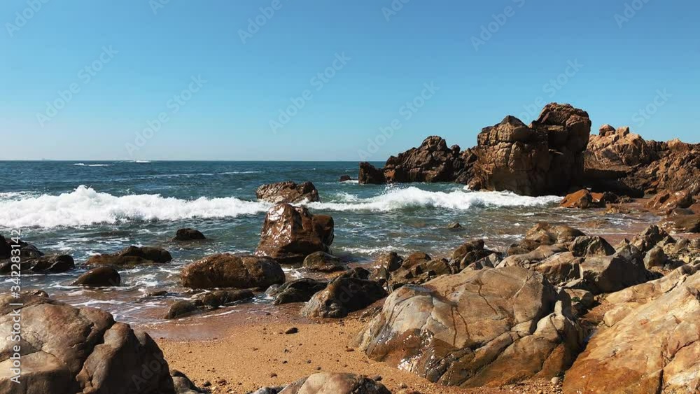 Breathtaking view of marina beach with massive stones rocks in daylight. Sea waves crashing on rocky coastline with spray and foam. On rocky shore of ocean. Slow motion.Concept of seascape.