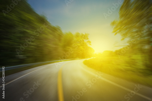 Asphalt road in motion blur of speed effect through and sunset