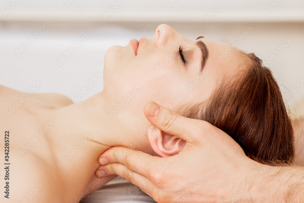Close up young woman receiving neck massage by hands of massage therapist.