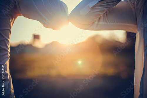 Elbow greeting to avoid the spread of coronavirus COVID-19. Business mans meet at sunset with bare hands. Instead of greeting with a hug or handshake, they bump elbows instead. photo