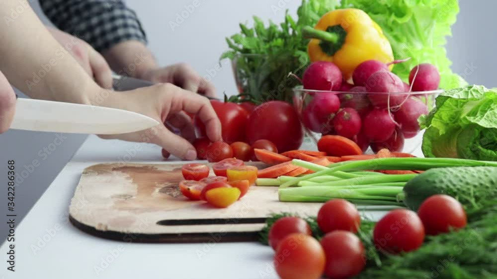 Close-up of female and male hands cutting vegetables on the table against the background of fresh vegetables.Family salad preparation. the concept of healthy food. Close-up of female and male hands cutting vegetables on the table against the background of fresh vegetables.Family salad preparation. the concept of healthy food.