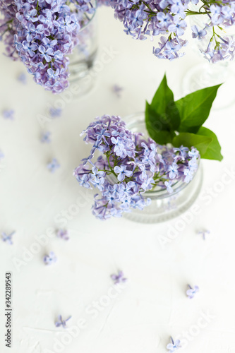 Fresh lilac flowers in a glass vase on the white table. Spring concept.