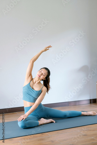 A young Asian woman practicing yoga indoors