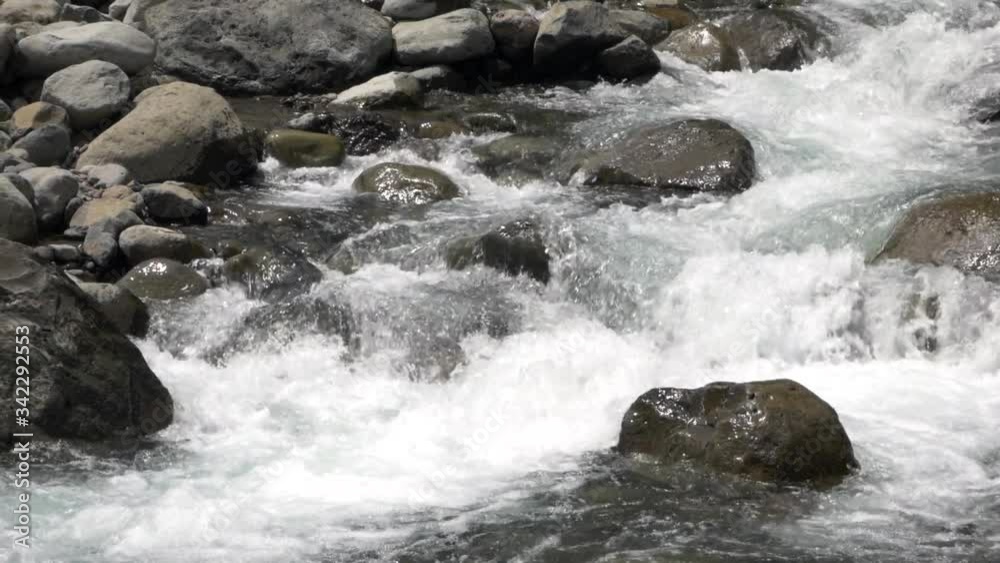 Rushing water flowing over round river rocks in a tropical stream, Iao Valley State Park, Maui, Hawaii, slow motion Rushing water flowing over round river rocks in a tropical stream, Iao Valley State Park, Maui, Hawaii, slow motion