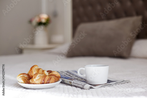 Wallpaper Mural A plate of fresh croissants, a Cup of coffee, and a morning newspaper lie on the bed in the bright room. Romantic breakfast. Space for text Torontodigital.ca