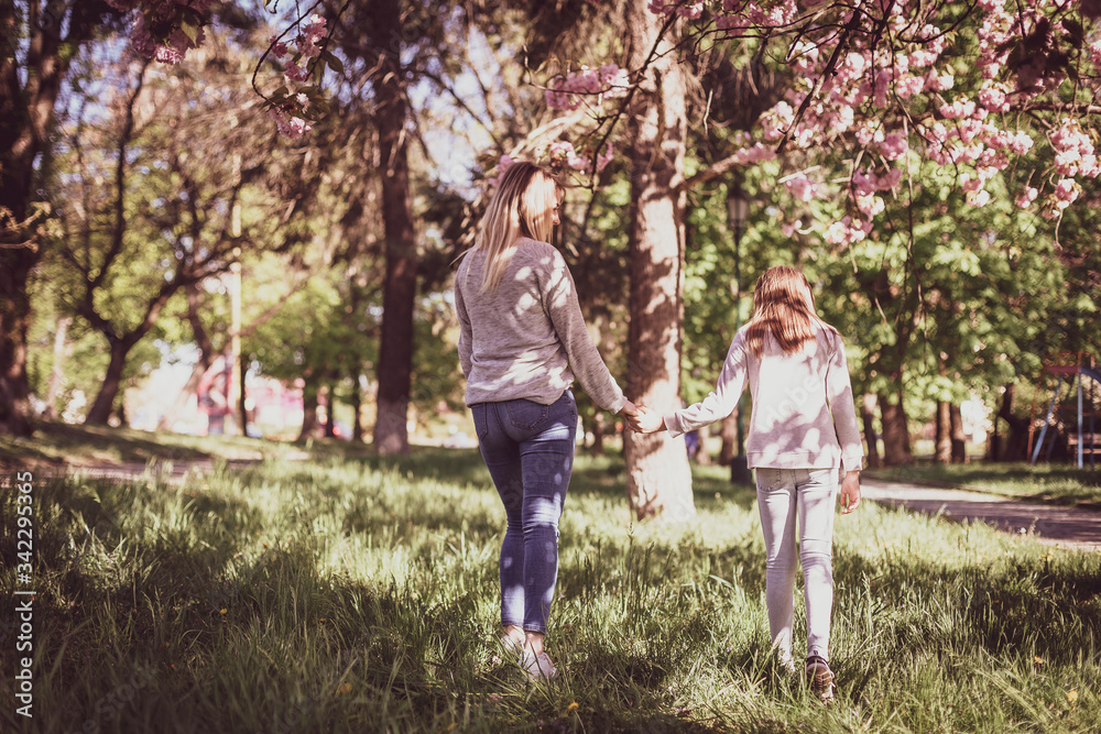 Sakura blossomed. Young mother with her child have fun in the park near the sakura. Spring morning. They look at each other