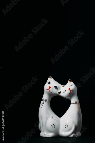 figurine of two white cats on a black background