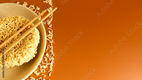 dry instant noodles in a typical circle shape on a plate with chopsticks. The effect of instant noodles on human health. pasta, for the preparation of which it is enough to pour boiling water.