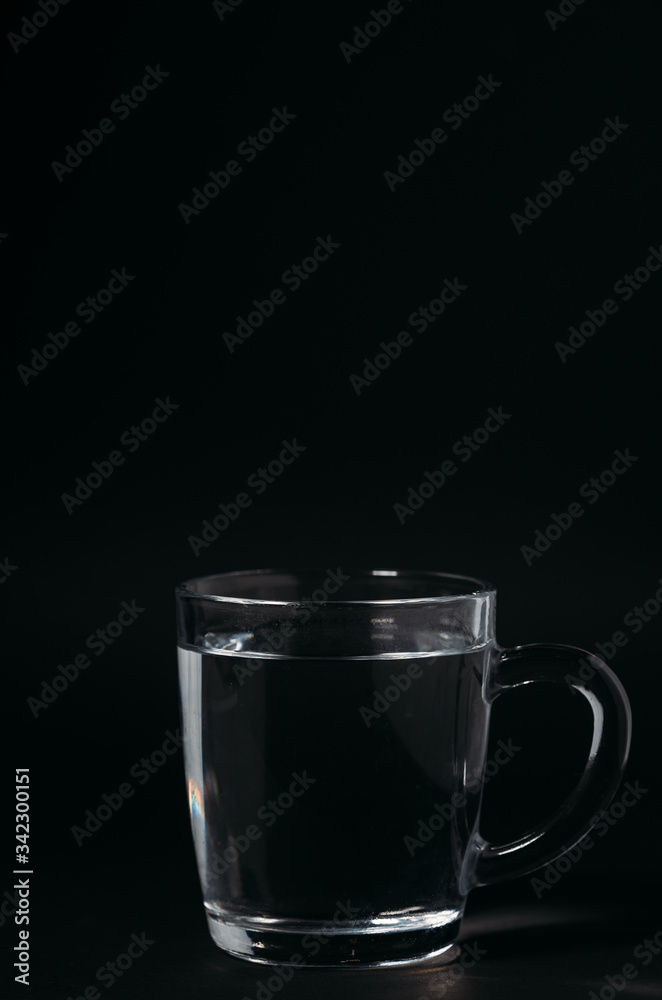 Glass with water on a black background. Cup of water. Glass with water on a black background. Cup of water.