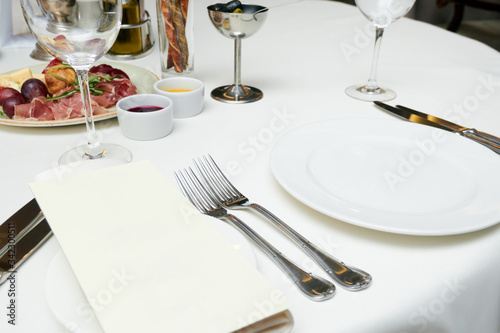 Serving and decor of white dishes, glasses, Cutlery on the table in a restaurant before dinner