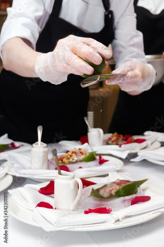 Close-up of cooking a dish of fillet of meat and sauce in a round white plate by a waiter in a restaurant before a romantic dinner at a Banquet on Valentine's day. The chef prepares the dish