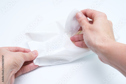 Woman hands taking wet cleaning antibacterial wipes out of package  white background  hygiene and body care concept