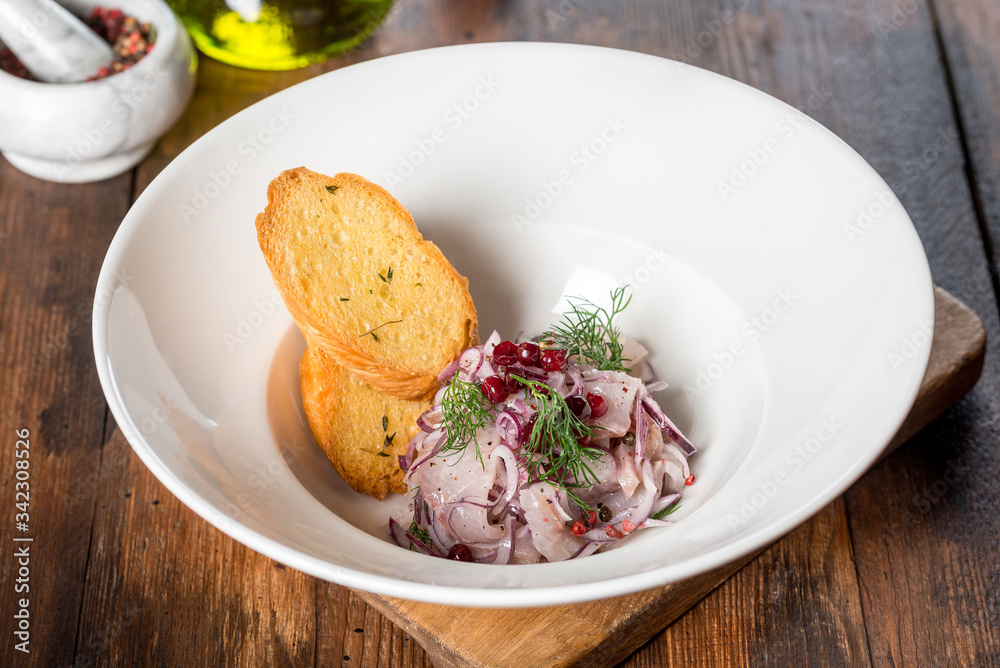 Herring appetizer served with bread in a white plate