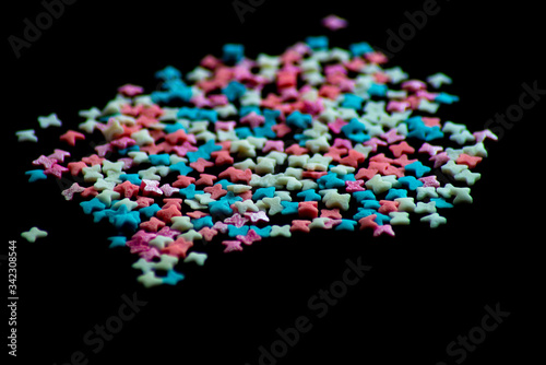 multicolored confectionery sprinkle in the form of butterflies on a black background