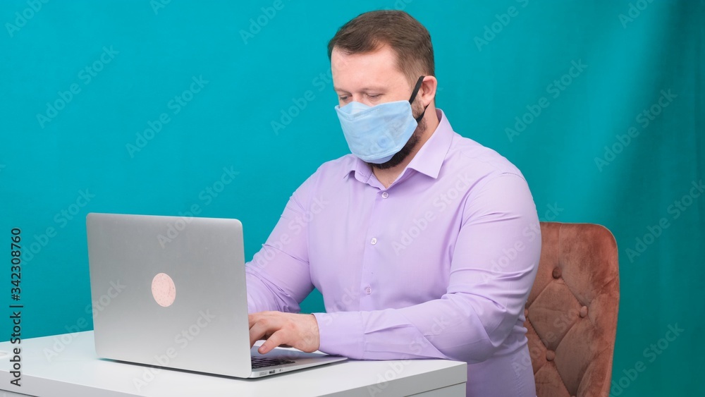 Side view portrait of a cheerful brunette man with surgical medical mask working on email laptop typing or chatting in social. Side view portrait of a cheerful brunette man with surgical medical mask working on email laptop typing or chatting in social.