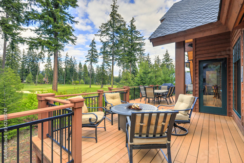 Beautiful large cabin home  with large wooden deck and chairs with table overlooking golf course Fototapet